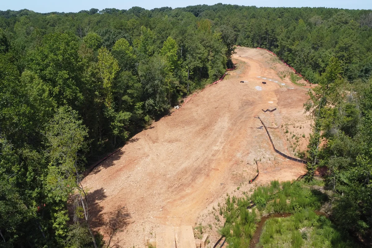 Aerial view of a cleared and graded corridor through Georgia woods, red clay shaped and ready for the next phase