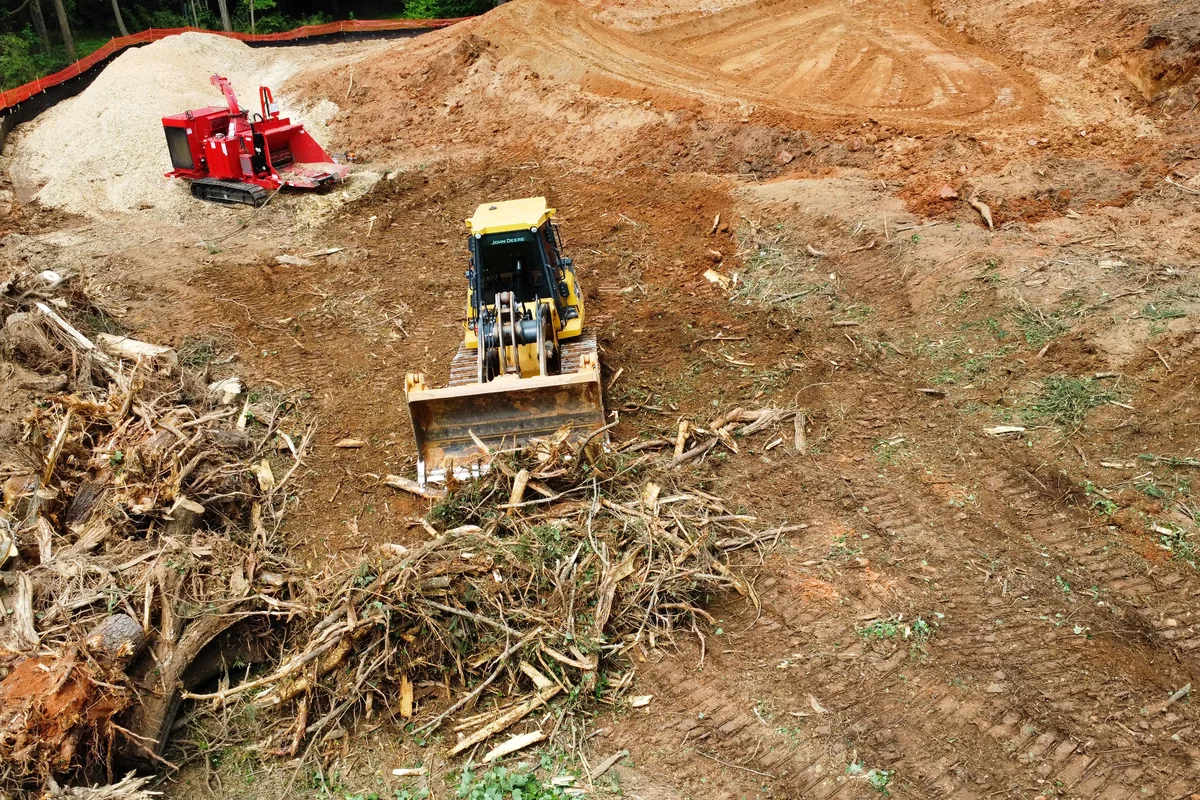 Dozer pushing stumps and cleared debris toward a horizontal grinder on a red clay site in Georgia